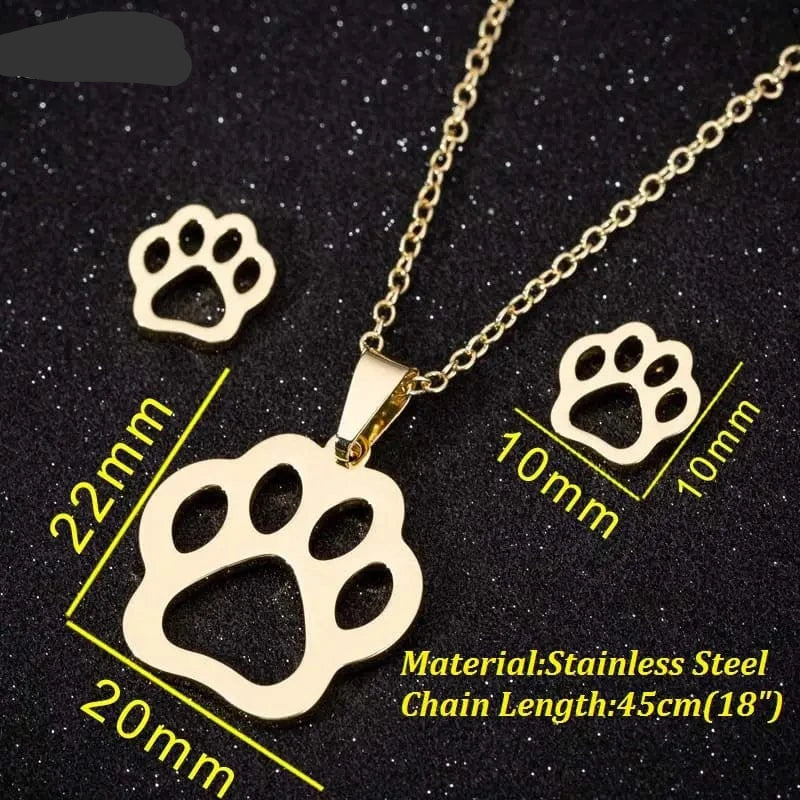 Gold paw print necklace and earrings with measurements on a black background