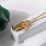 Gold necklace with paw print pendant on a white surface