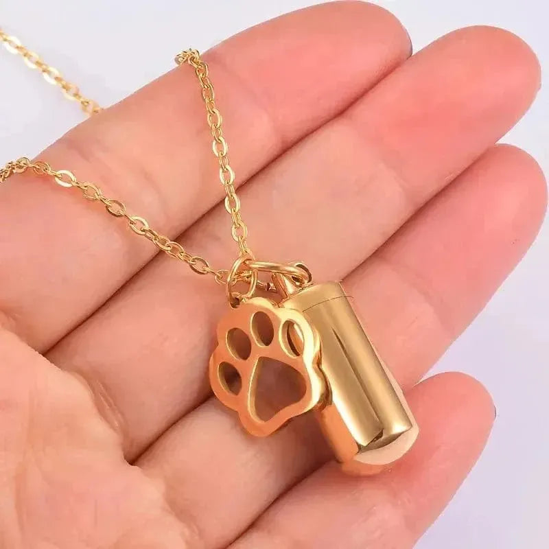 Gold necklace with a paw print pendant held in a hand against a white background