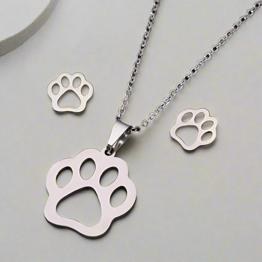 Silver paw print necklace with matching paw print pendants on a light gray background
