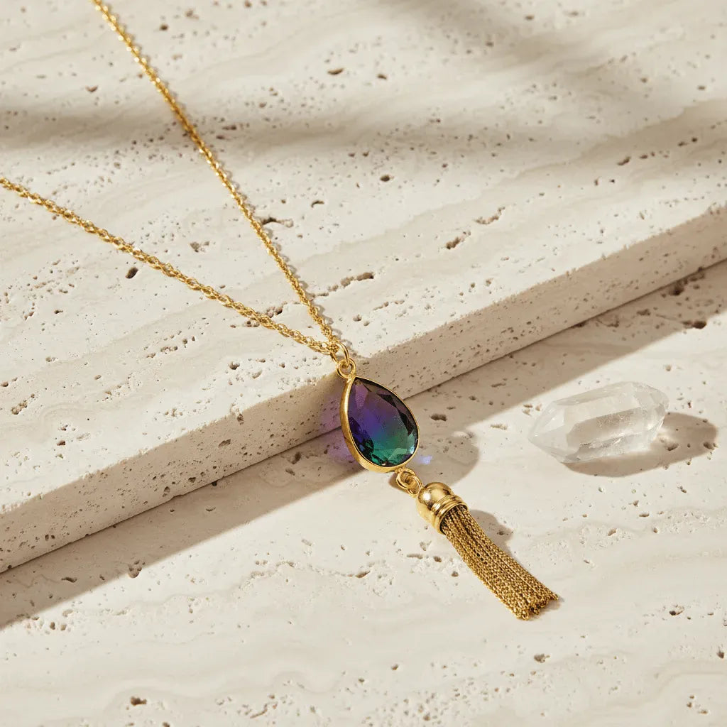 Necklace with a teardrop-shaped pendant and tassel on a textured surface