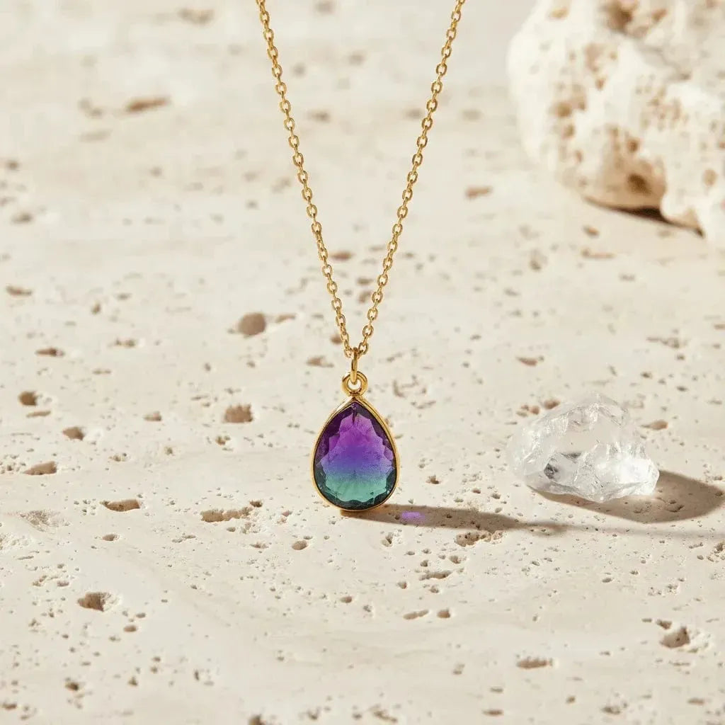Necklace with a teardrop-shaped gemstone pendant on a sandy surface