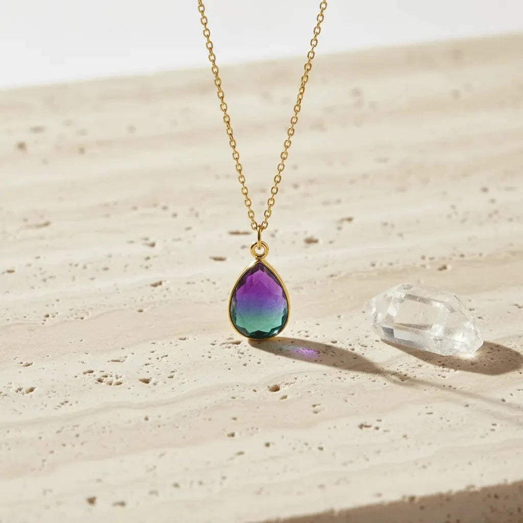 Necklace with a teardrop-shaped pendant on a sandy surface