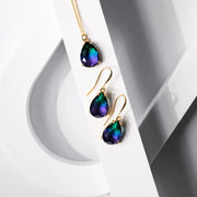 Teardrop-shaped earrings with gold settings on a white and gray background