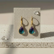 Peacock ombré mini drop earrings in gold on a display card