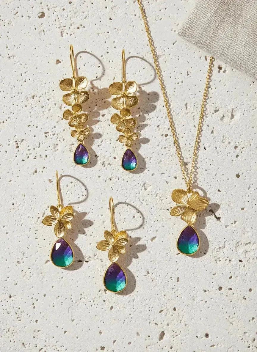 Jewelry set with gold floral earrings and necklace on a textured surface
