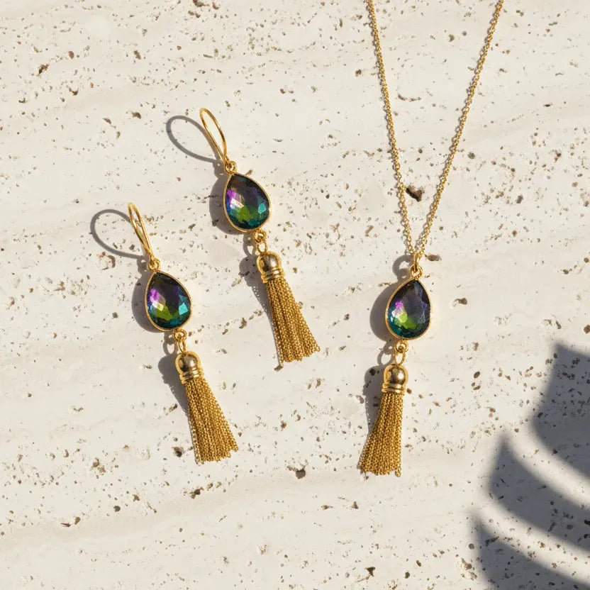 Gold necklace and earrings with tassels on a textured surface