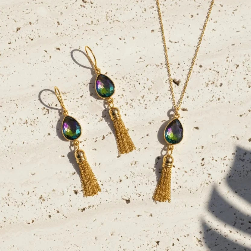 Gold necklace and earrings with tassels on a textured surface