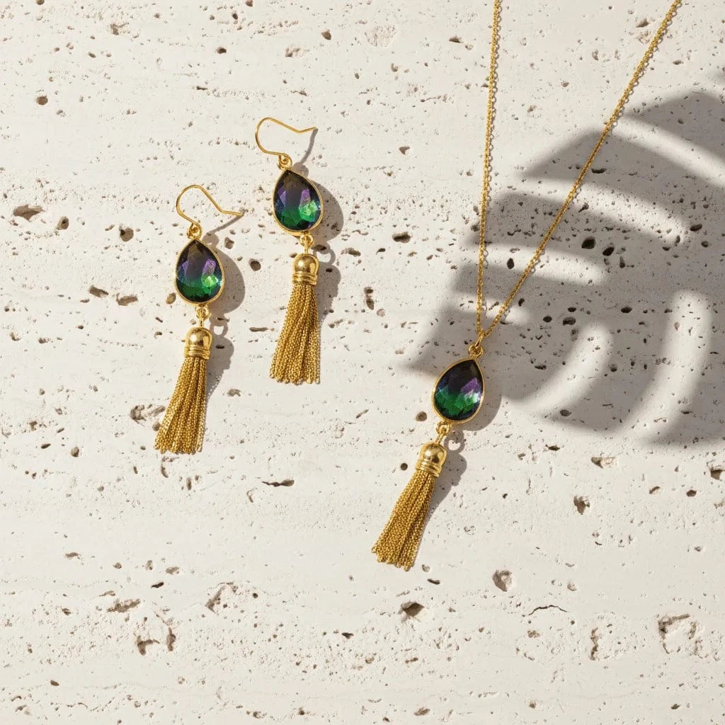 Gold tassel necklace and earrings on a textured beige surface