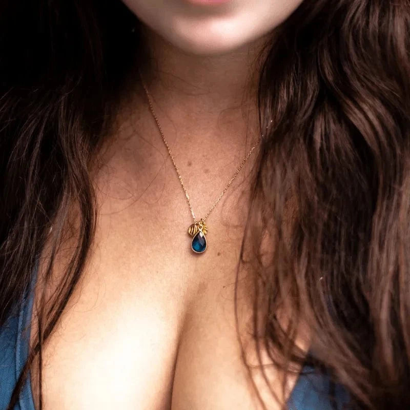 Close-up of a necklace with a blue pendant worn by a person with long hair.