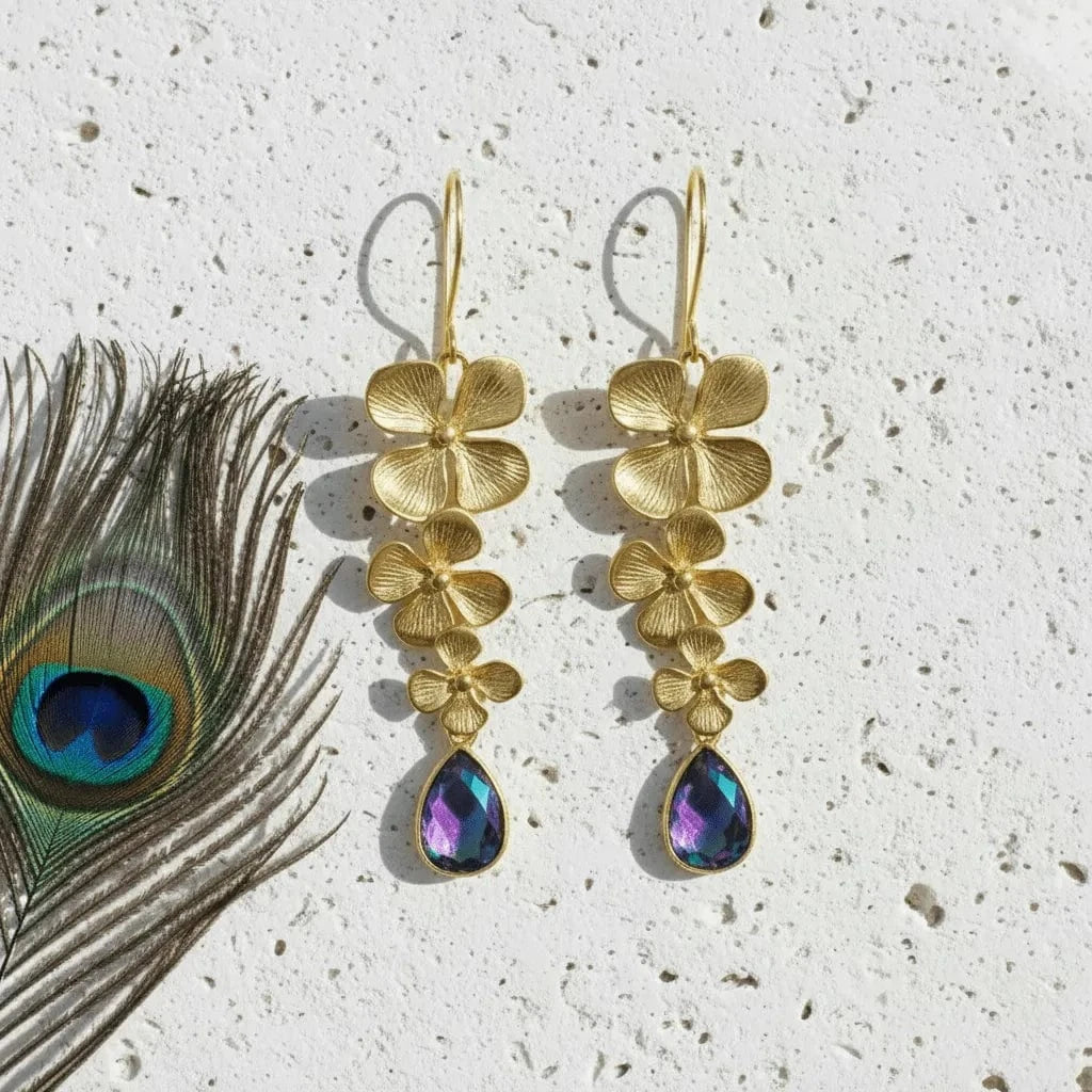 Three-bloom plumeria earrings in peacock ombré hydro quartz beside a peacock feather