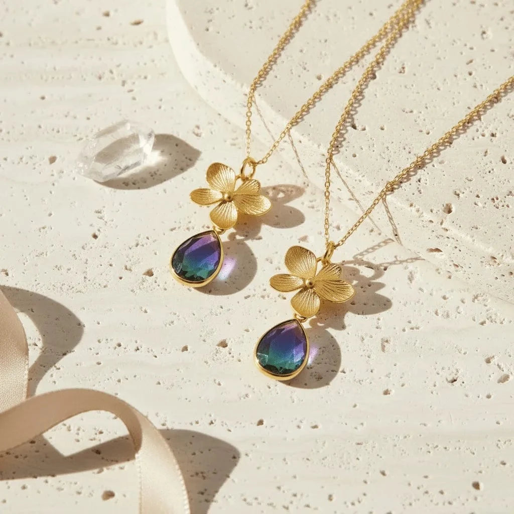 Gold necklace with floral pendants on a textured beige surface