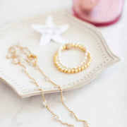 Pearl necklace and bracelet on a decorative plate with a pink heart in the background