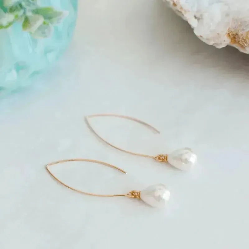 Pearl earrings with gold hooks on a light background
