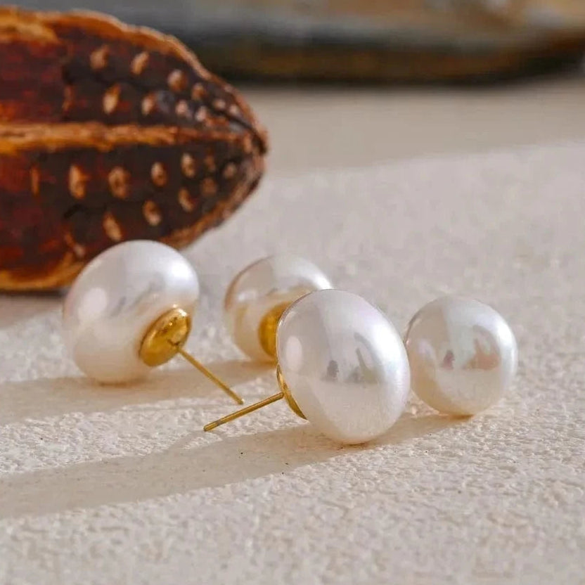 Pearl earrings on a textured surface with a blurred background