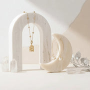Jewelry display with gold necklaces on a neutral background, featuring text about planetary elegance.