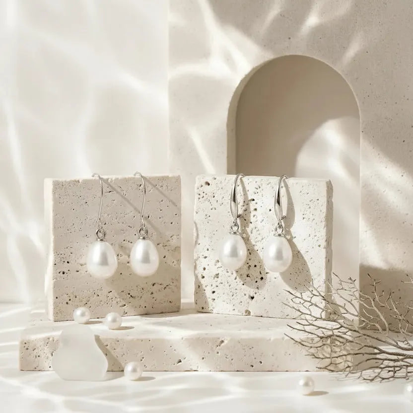 Pearl drop earrings displayed on a stone surface with text about their symbolism.