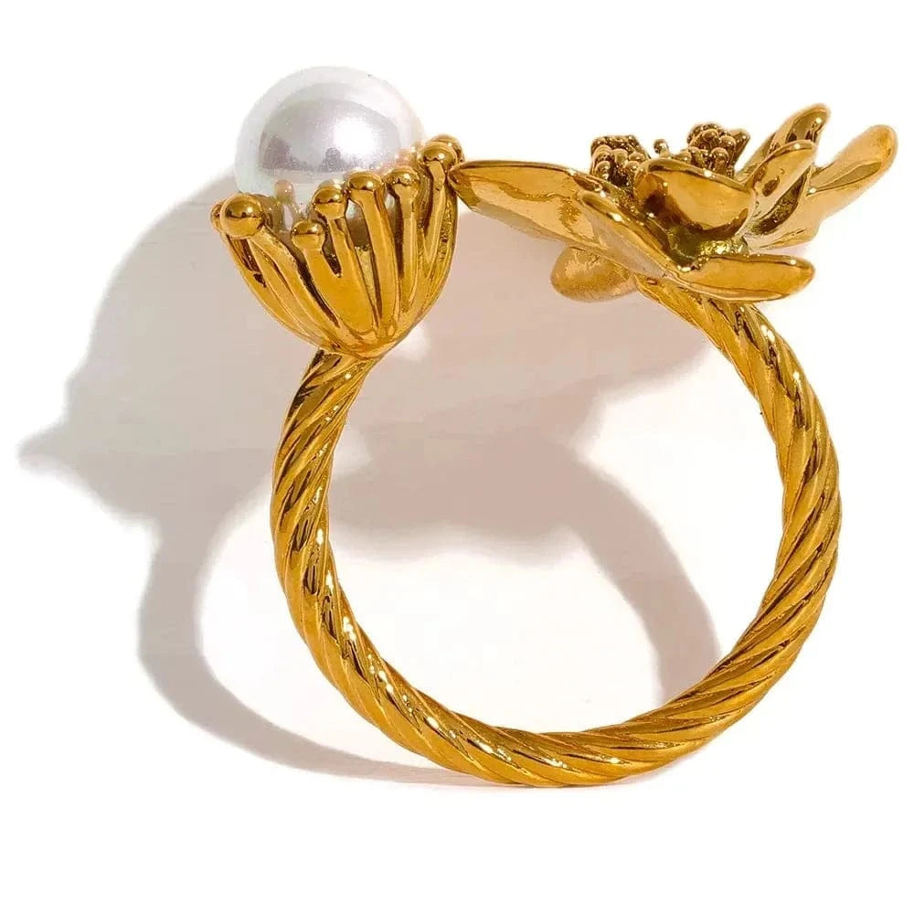 Gold ring with floral design and pearl on a white background