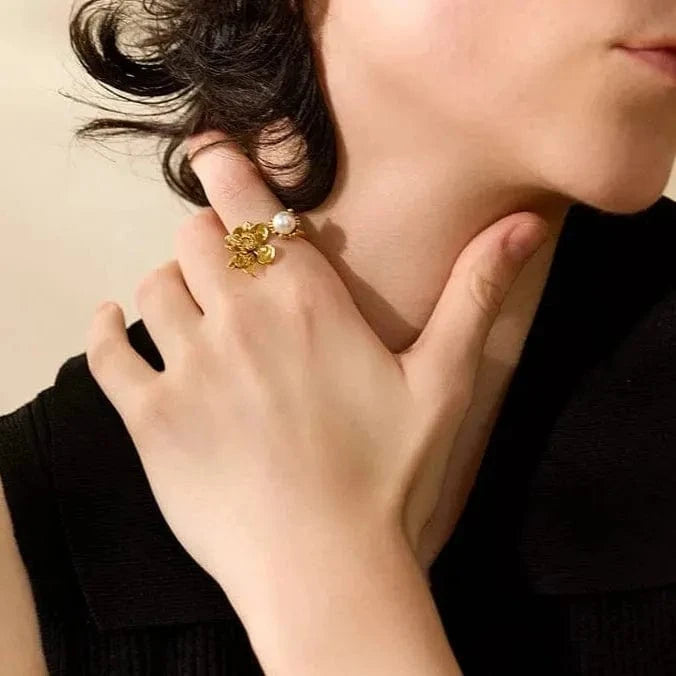 Person wearing a gold ring on their finger, with a neutral background
