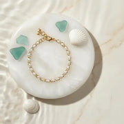 Pearl bracelet on a white stone with green stones and shells