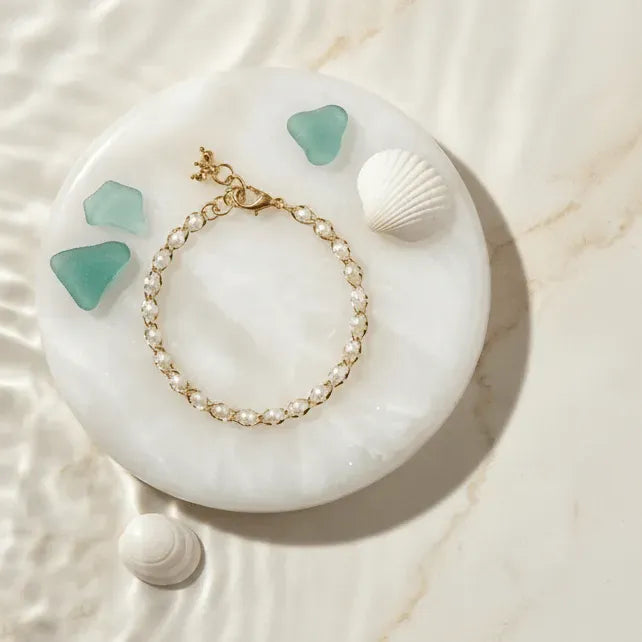 Pearl bracelet on a white stone with green stones and shells