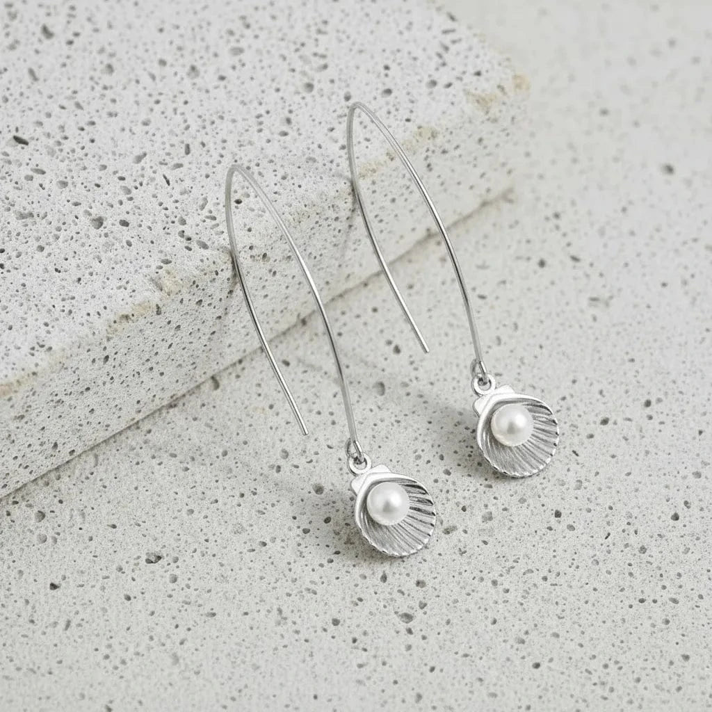 Silver earrings with pearl-like beads on a textured surface