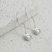 Silver earrings with pearl-like beads on a textured surface