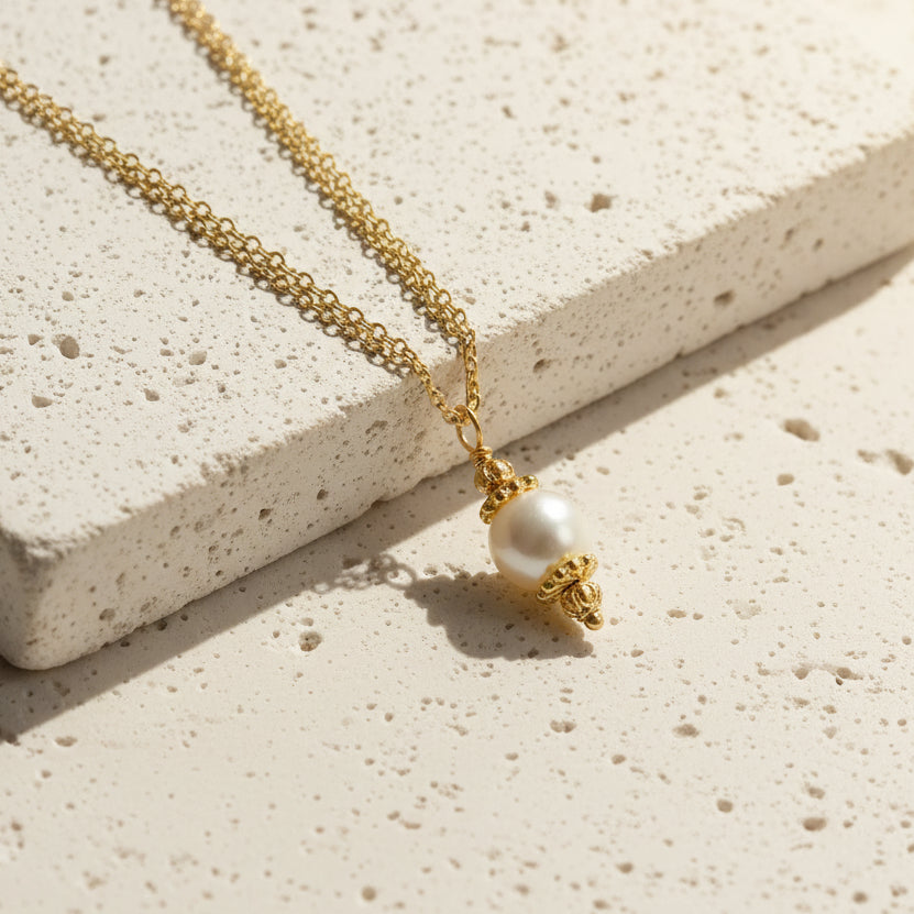 Gold necklace with a pearl pendant on a white background