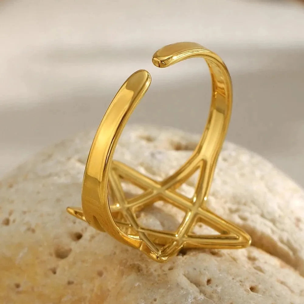 Gold open ring with geometric design on a textured beige surface