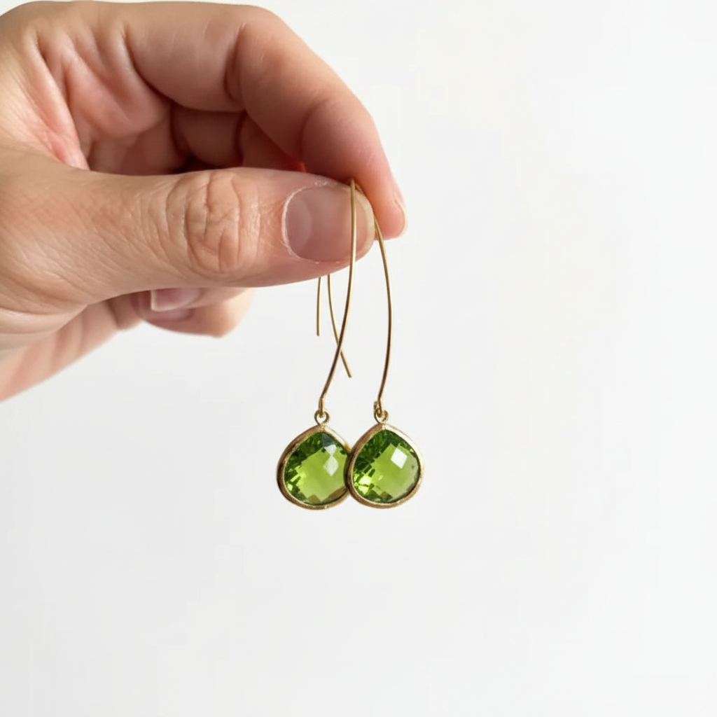 Peridot Elegant Pebble earrings held in hand, faceted green glass
