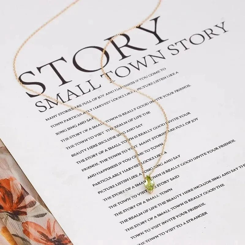 Necklace with a green pendant on a sheet of paper with text and floral design.