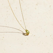 Gold necklace with a green pendant in a wooden box