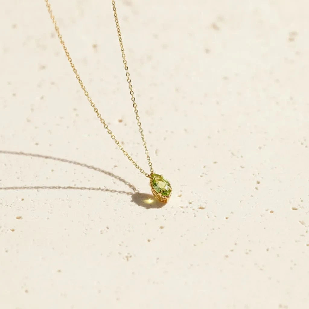Gold necklace with a green pendant in a wooden box