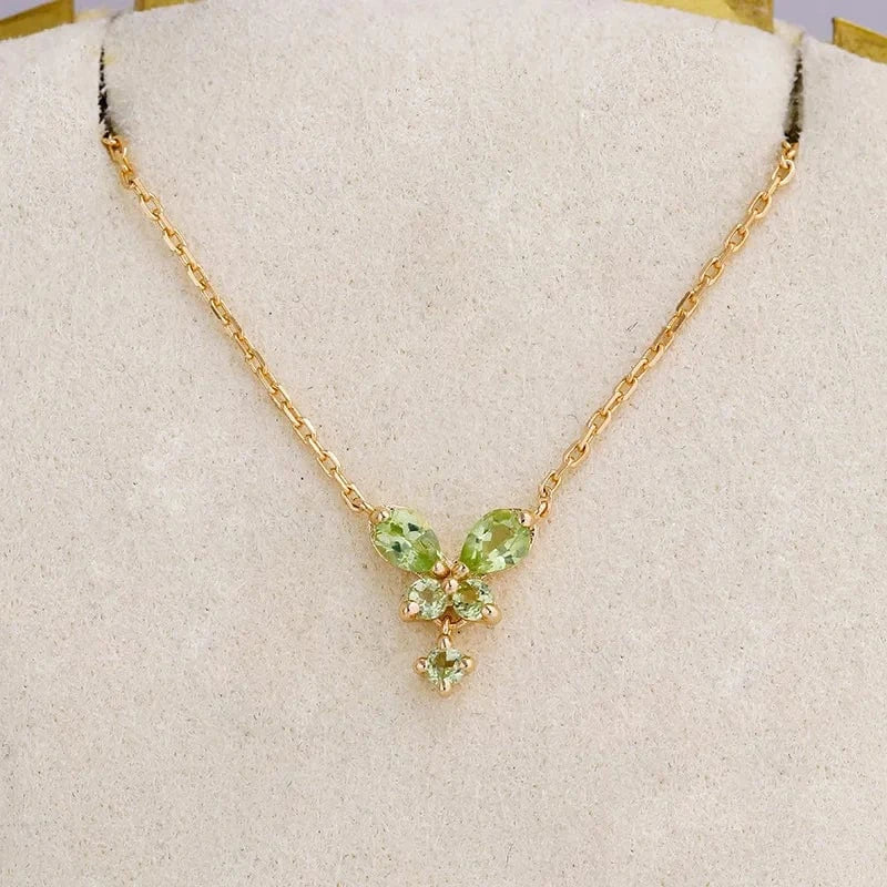 Gold necklace with green gemstones on a white cushion