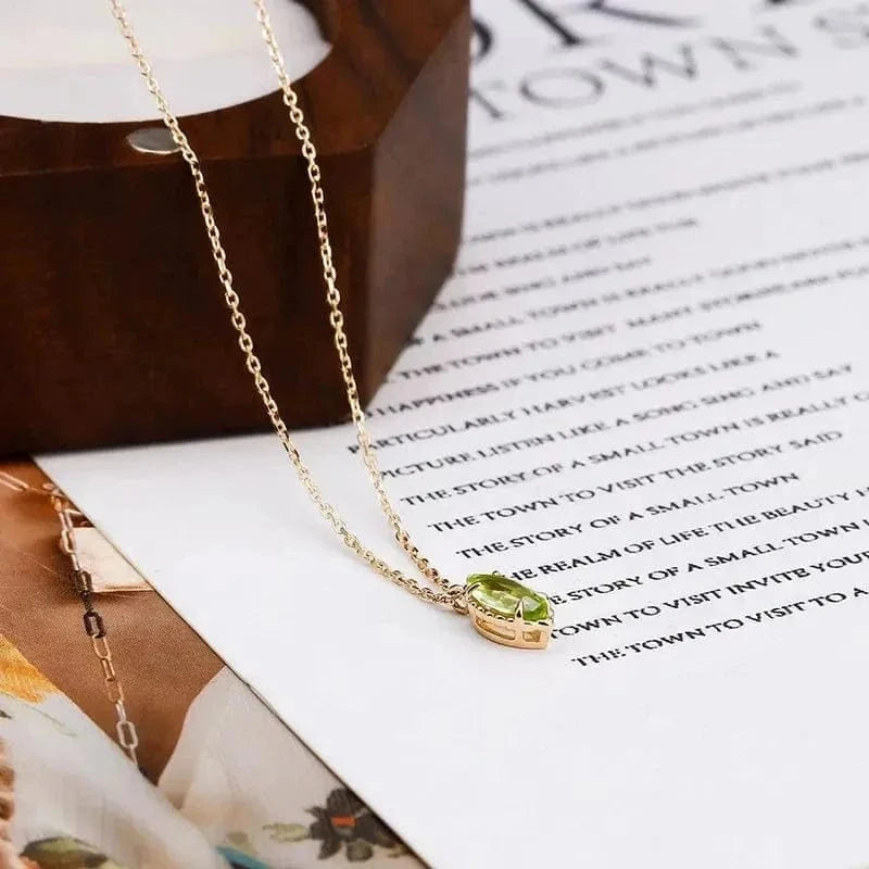 Gold necklace with a green gemstone pendant on a magazine page