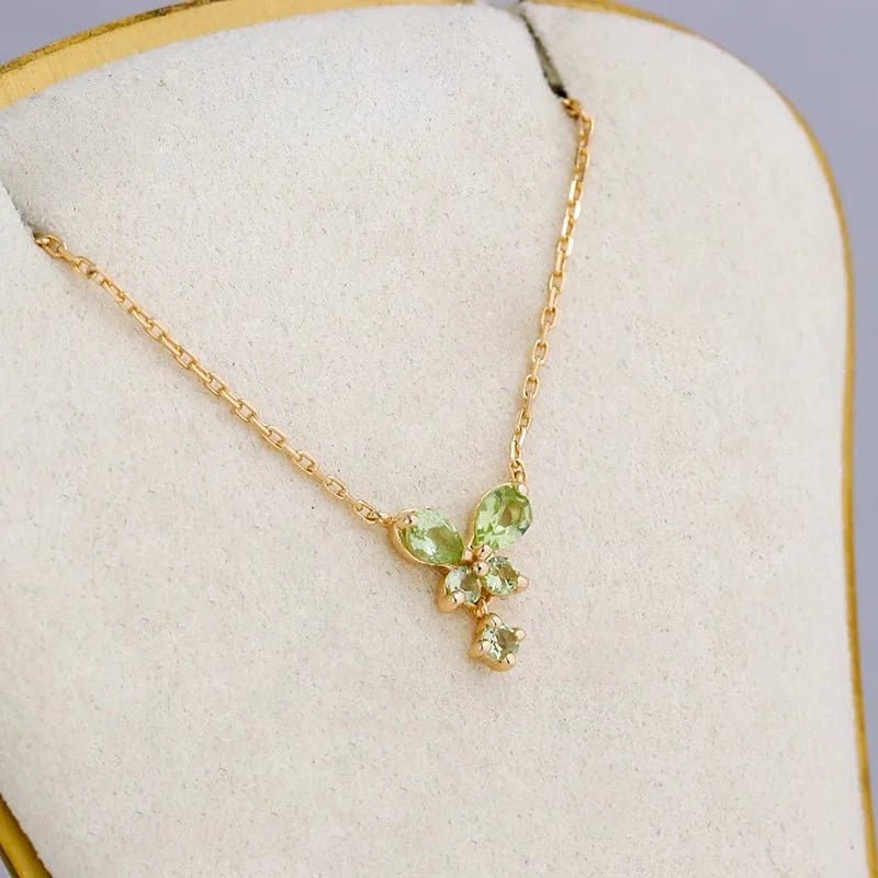 Gold necklace with green gemstones on a white cushion