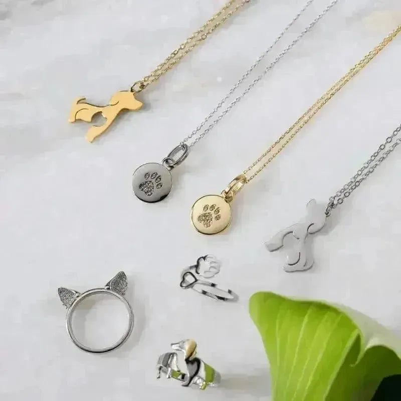 Collection of animal-themed jewelry including necklaces and rings on a light background.
