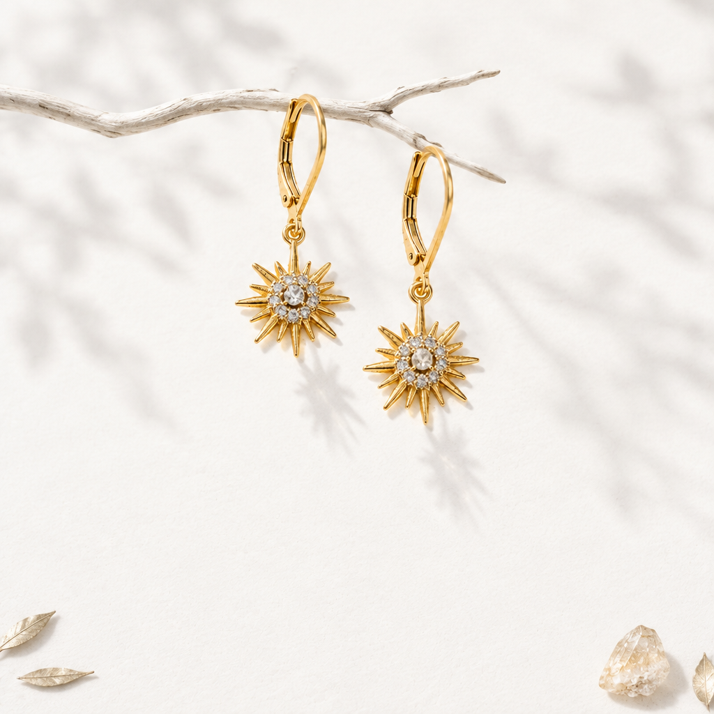 Petite gold star drop earrings with CZ halo hanging from a branch