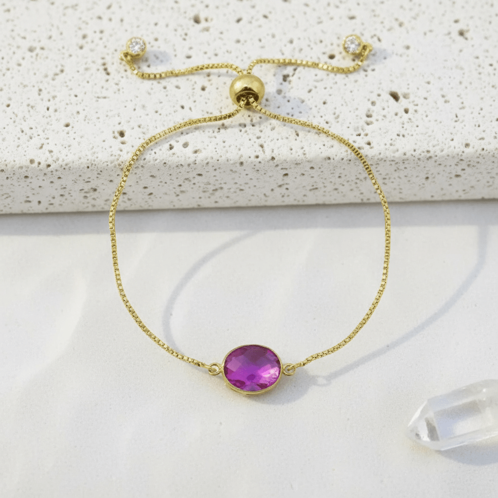 Gold bracelet with a purple gemstone on a textured surface
