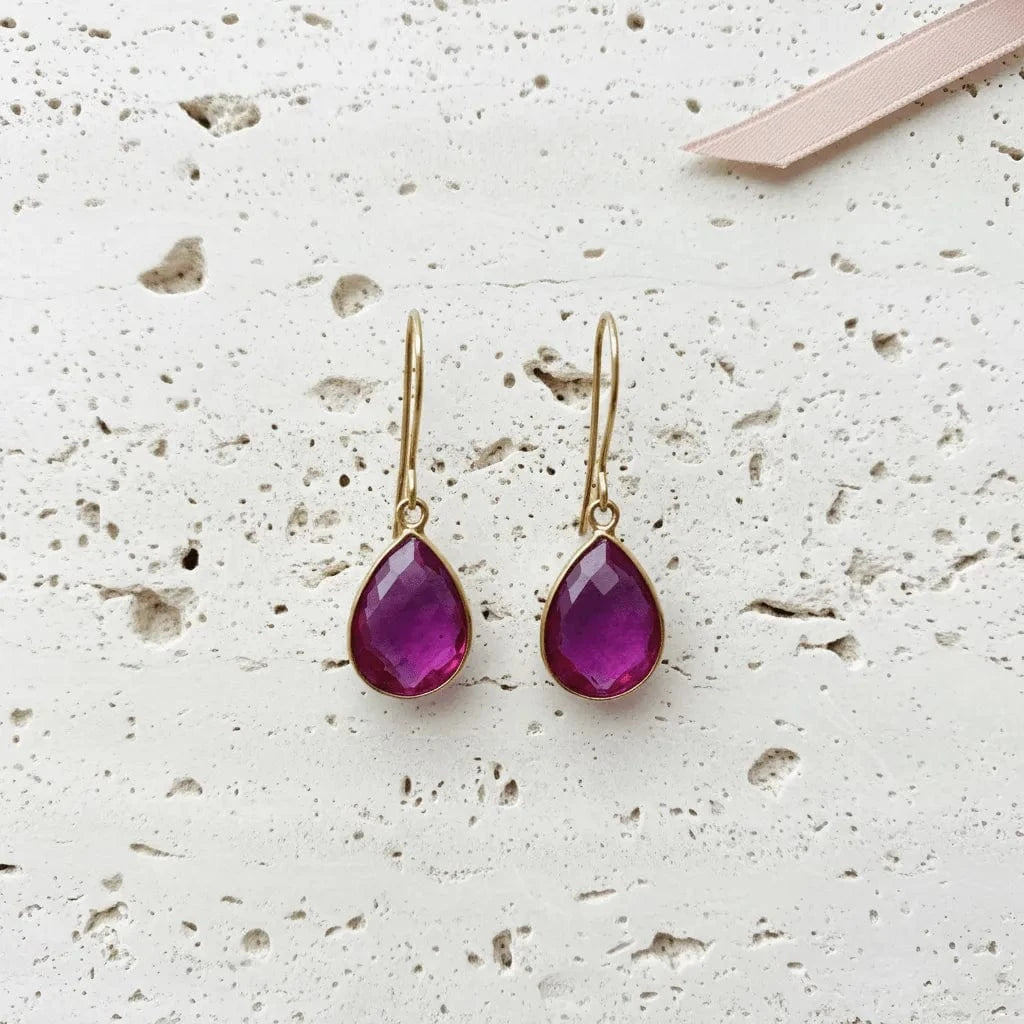 Pair of purple teardrop earrings on a textured white surface