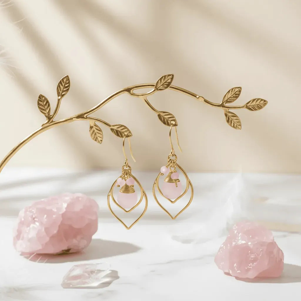 Gold earrings with pink stones on a decorative branch and white surface