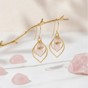 Gold earrings with pink stones on a soft beige background
