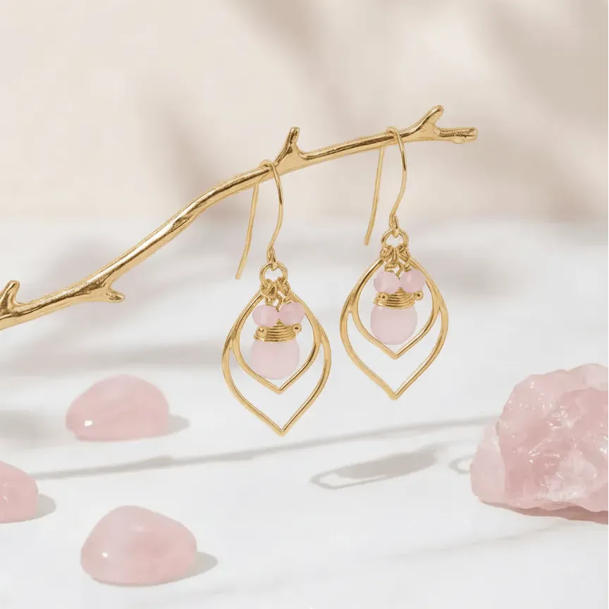Gold earrings with pink stones on a soft beige background
