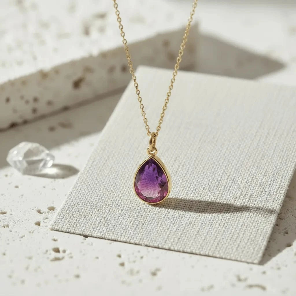 Necklace with a purple teardrop pendant on a textured surface