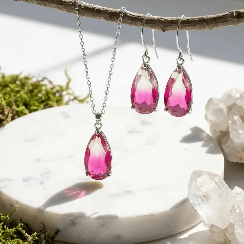Pink teardrop earrings hanging from a branch with a natural background