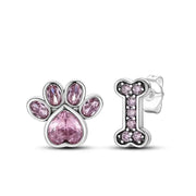 Silver earrings with pink gemstones shaped like a paw print and bone on a white background