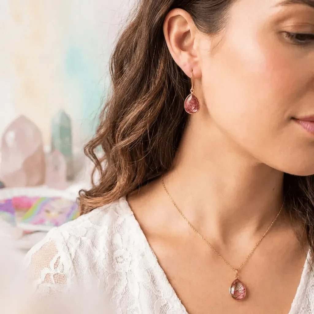 Woman wearing pink teardrop earrings and necklace with a blurred background