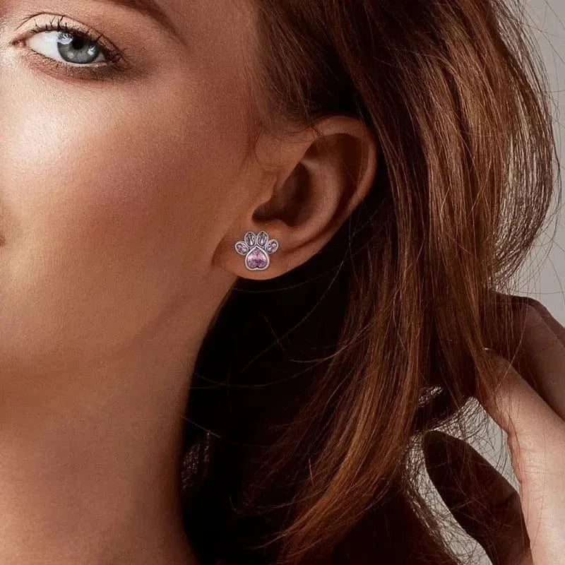 Close-up of a woman wearing a silver earring with a pink heart detail.