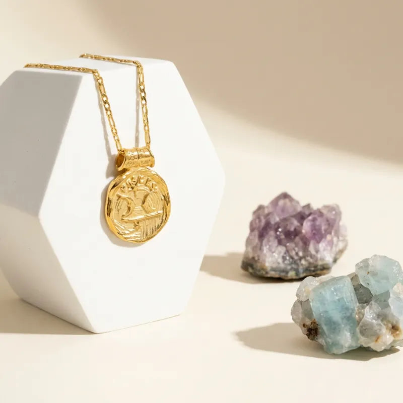 Gold necklace on a white stand with crystals on a beige background