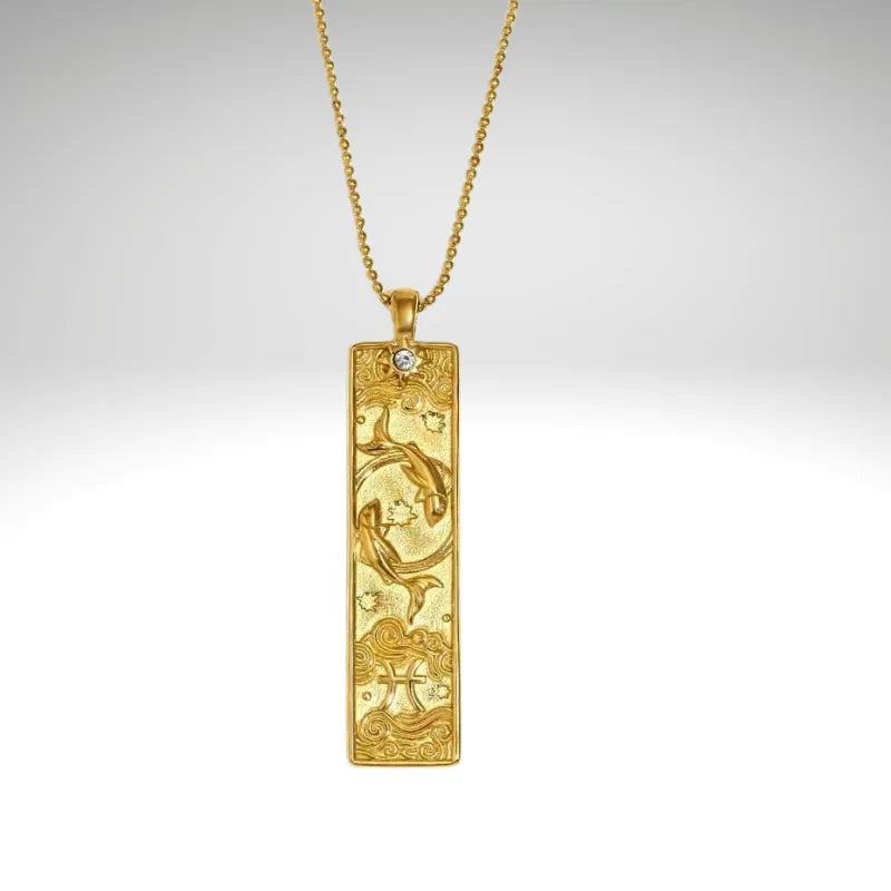 Gold pendant necklace with intricate designs on a light gray background
